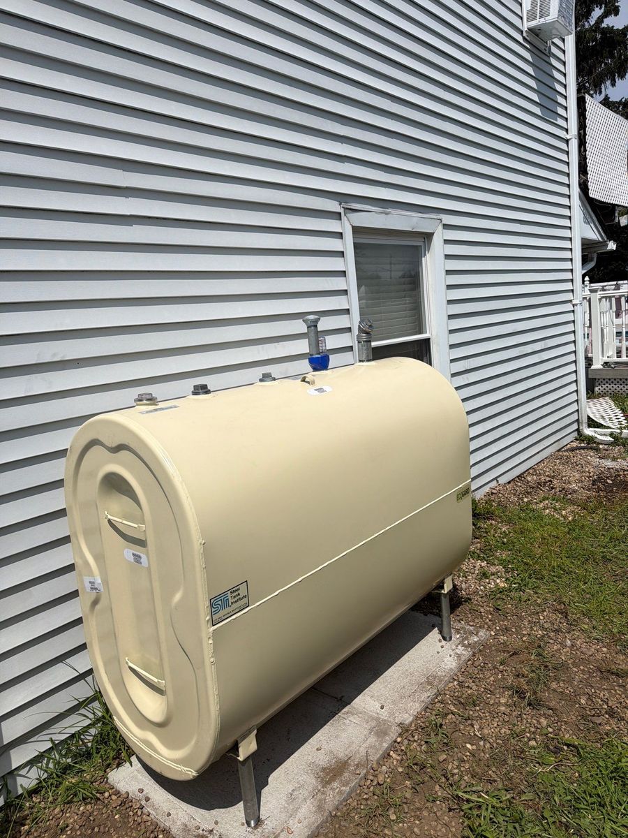 New outdoor 275-gallon heating oil tank installed on a concrete pad beside a home